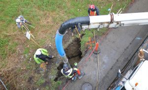 High angle view of a plumbing crew repairing a sewer line without digging a massive trench.