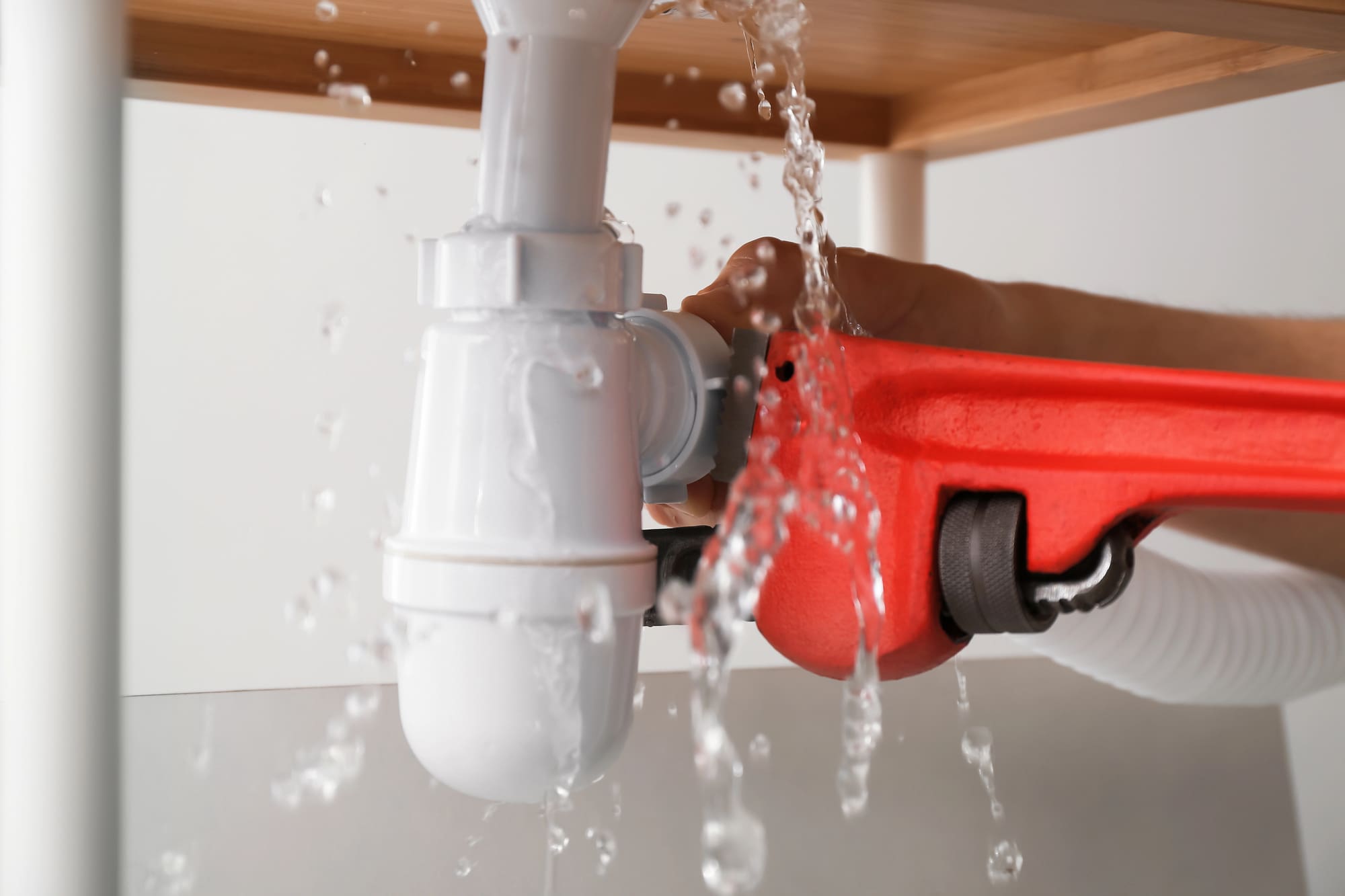 General plumbing services San Francisco technician fixing a leaking pipe with a wrench in an emergency repair.